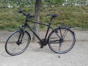 Kalkhoff Voyager Trekkingrad in Seitenansicht vor grüner Kulisse.