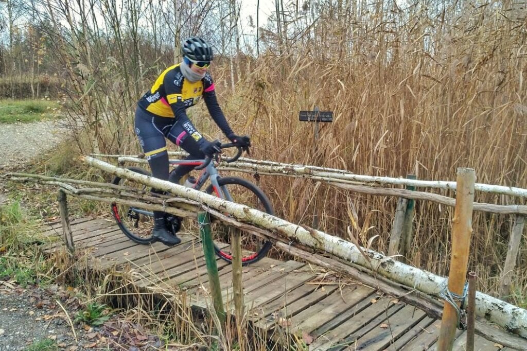 Radfahrerin fährt mit dem Cube Cross Race Pro Cyclocross-Bike über eine Holzbrücke.