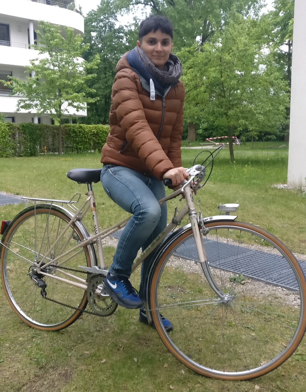 Junge Frau sitzt auf ihrem Fahrrad in grüner Kulisse