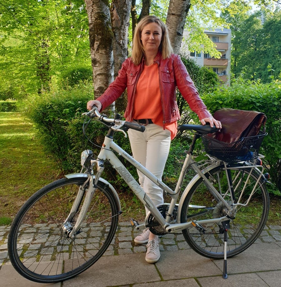 Frau steht neben ihrem Fahrrad und lächelt