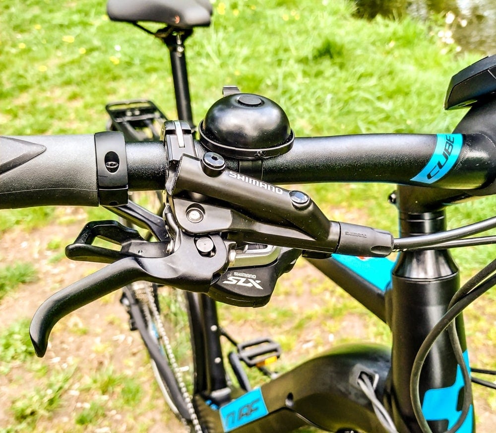 Nahaufnahme des Lenkers mit Klingel und Shimano SLX Schalthebel am Cube Kathmandu Hybrid EXC 500 E-Bike.