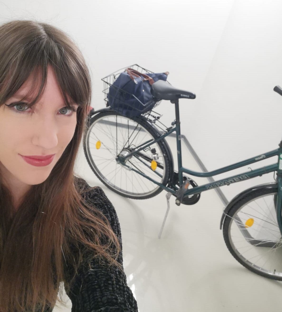 Selfie einer jungen Frau mit ihrem Fahrrad im Hintergrund