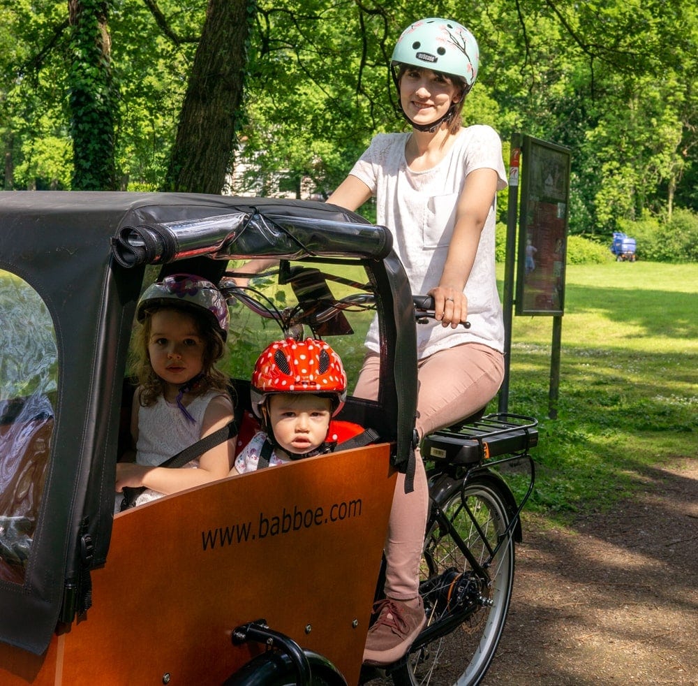 Testerin Nicola auf dem Babboe Big-E Lastenrad mit großer Transportbox mit zwei mitfahrenden Kindern.