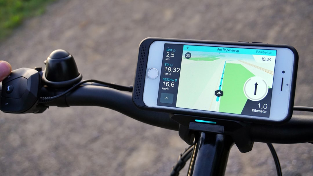 Nahaufnahme eines Smartphones mit geöffneter COBI.Bike-App am Lenker eines E-Bikes.