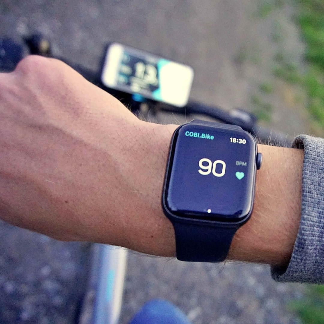 Nahaufnahme einer Apple Watch am Handgelenk mit Anzeige von Fahrdaten von der COBI.Bike-App.