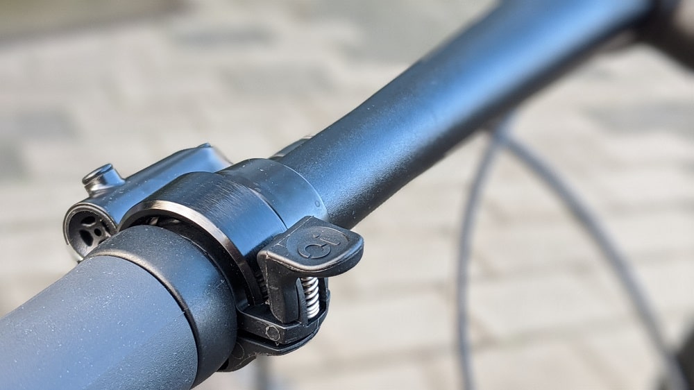 Nahaufnahme einer schwarzen Knog Oi Fahrradklingel am Lenker.
