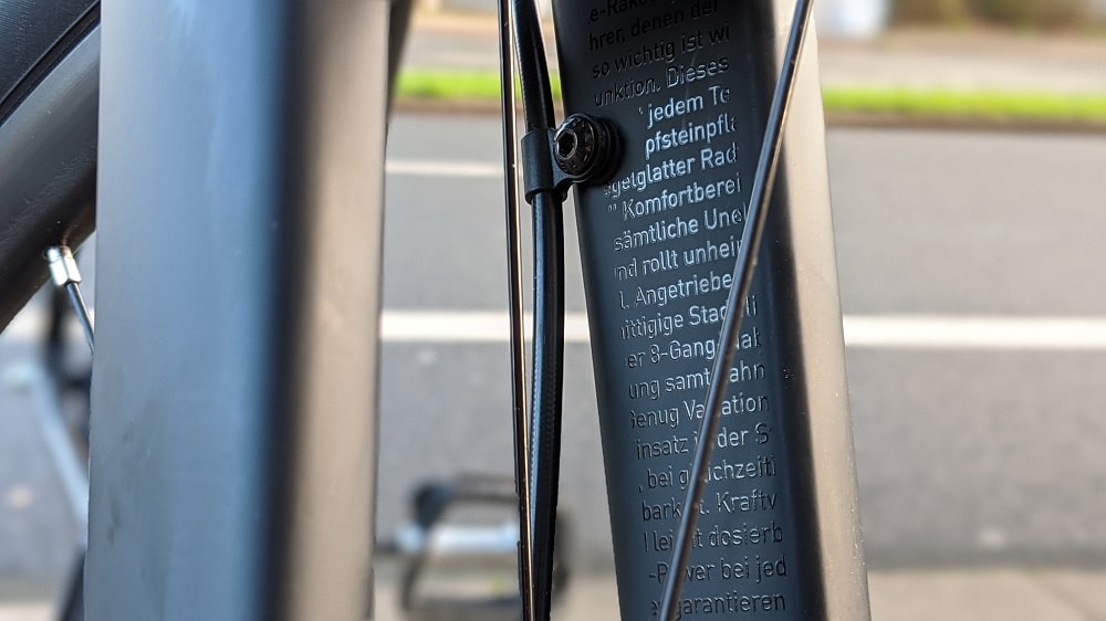 Nahaufnahme eines Fahrradrahmens mit Kabelzügen und aufgedrucktem Schriftzug.