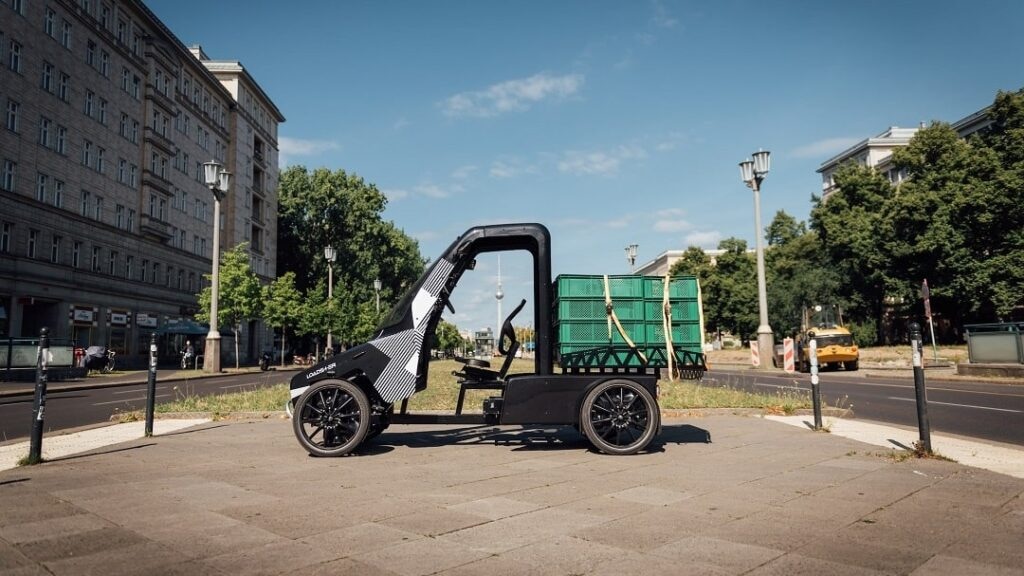 Citkar Loadster Lastenrad mit grünen Transportkisten auf einer Straße in der Stadt.