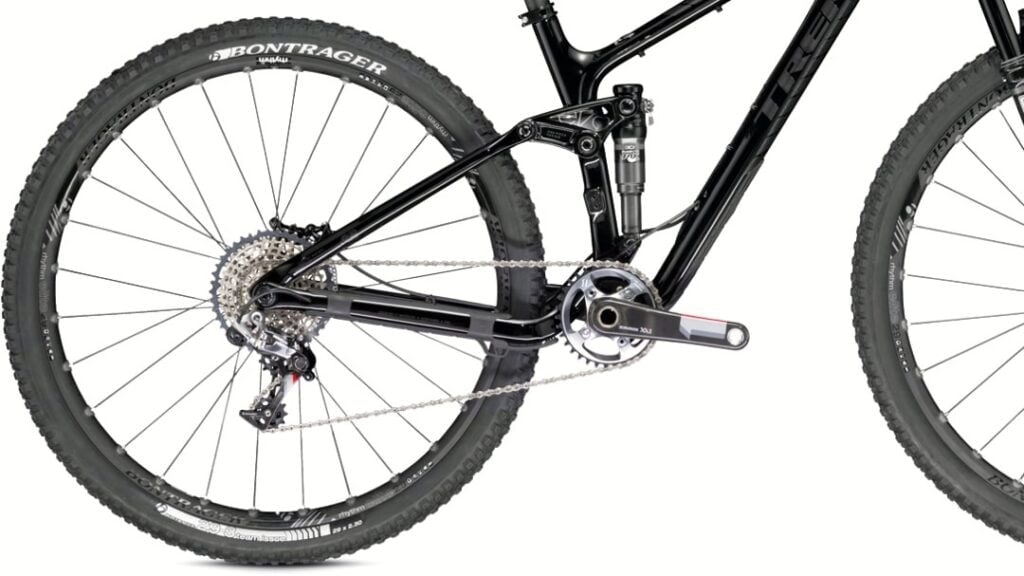 Nahaufnahme des Hinterbaus eines Mountainbikes mit Schaltwerk, Kassette, Kette, Kurbel und Dämpfer vor weißem Hintergrund.