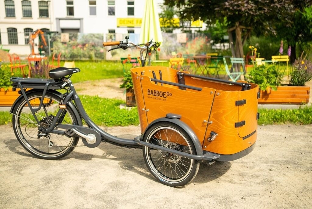 Babboe Lastenrad mit Transportbox auf einem Weg im Grünen.