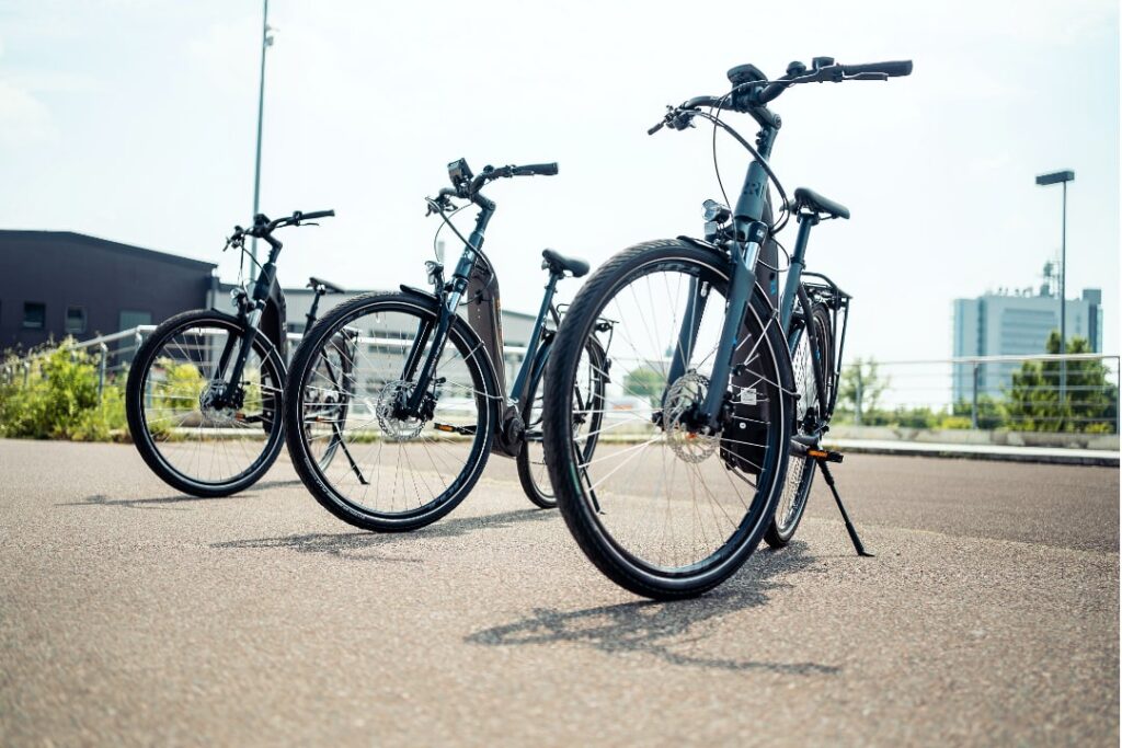 Drei 2R Manufaktur E-Trekkingbikes stehen nebeneinander im Freien.