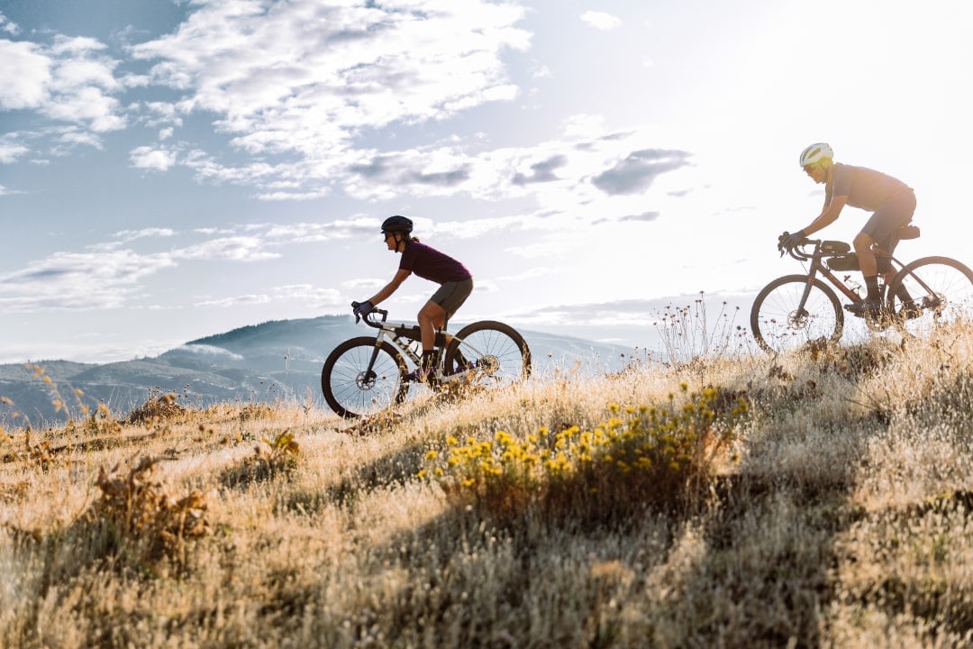 Zwei Gravelbiker fahren mit Trek Bikes durch eine hügelige Landschaft.