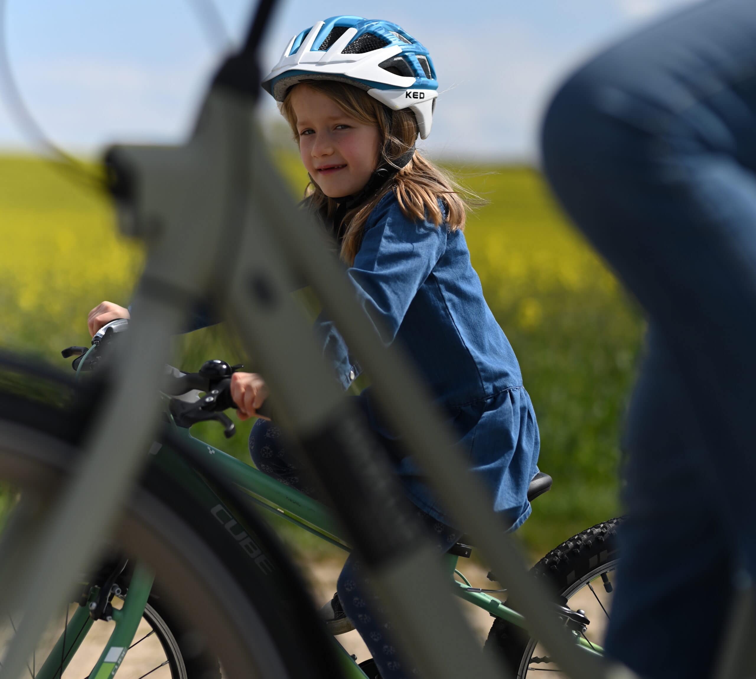 Kind mit Fahrradhelm auf einem Kinderfahrrad im Grünen.