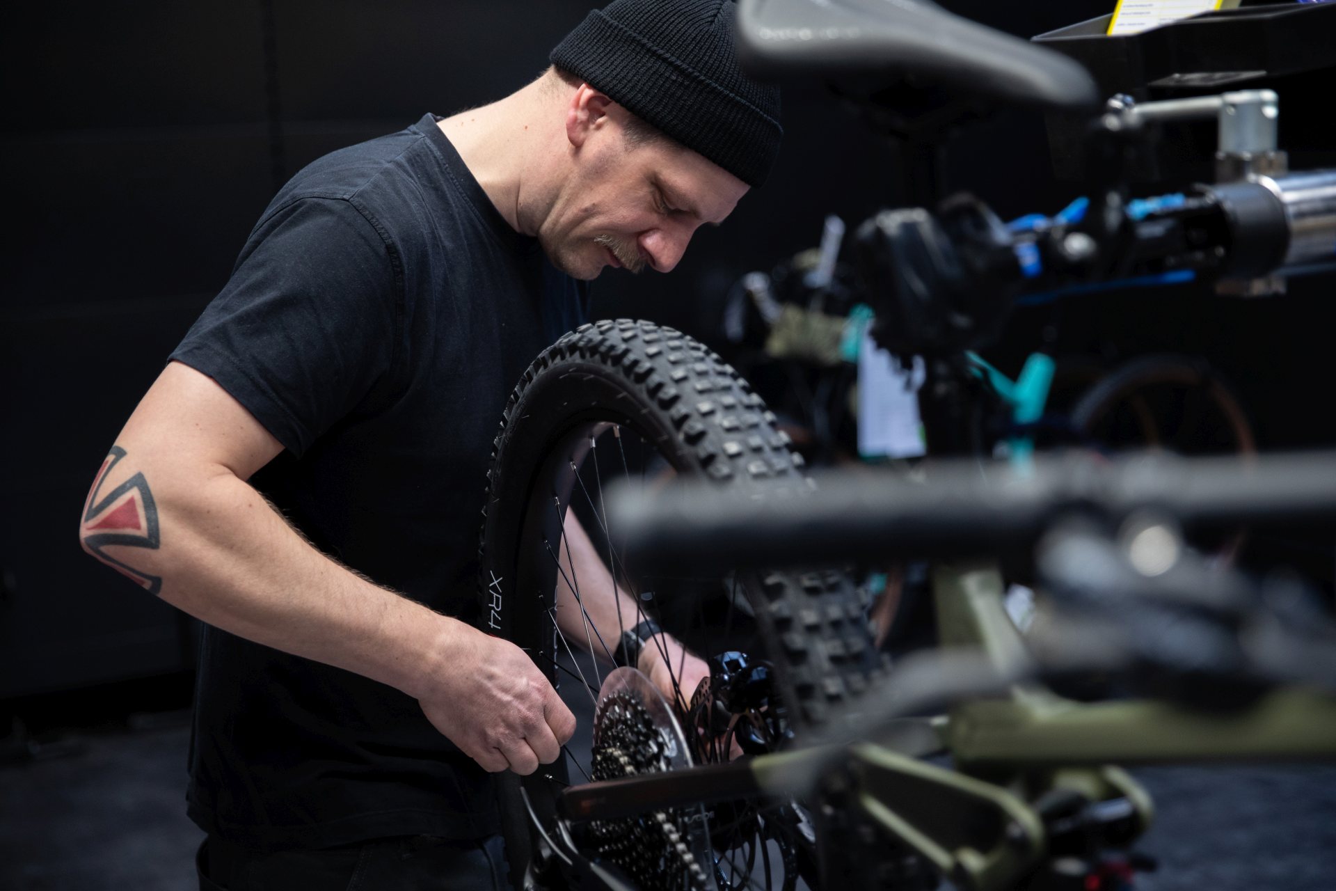 Fahrradmechaniker arbeitet am Hinterrad eines Mountainbikes in einer Werkstatt.