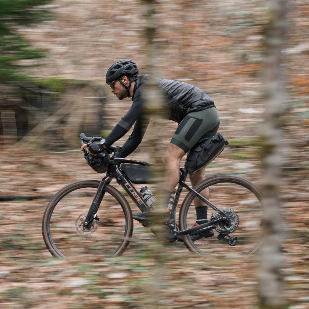 Radfahrer fährt mit hoher Geschwindigkeit durch eine Waldlandschaft.