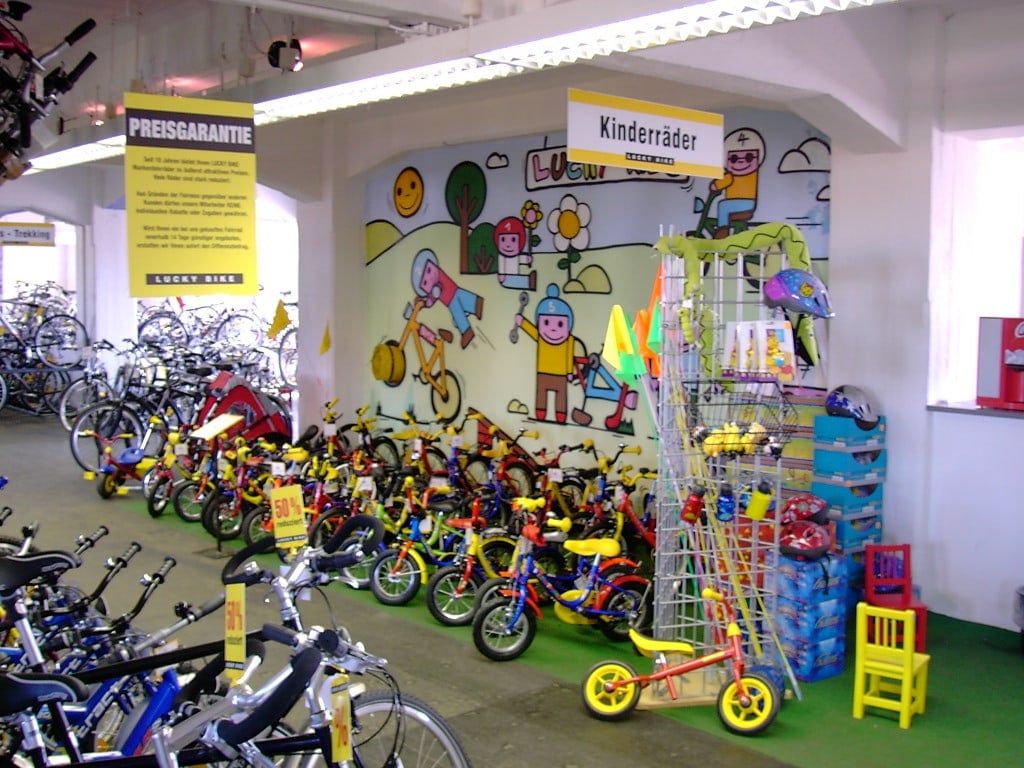 Kinderfahrräder und Fahrradzubehör in einem Fahrradgeschäft mit bunter Wandgestaltung.
