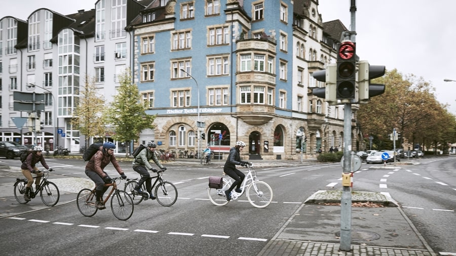 Vier Radfahrer fahren gemeinsam über eine Kreuzung in der Stadt.