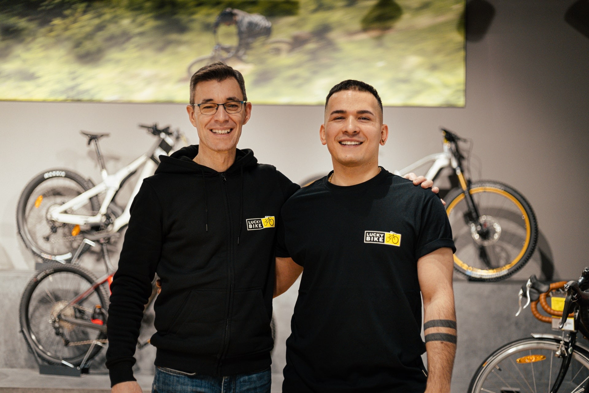 Mitarbeiter und Auszubildender von Lucky Bike stehen gemeinsam in einer Fahrradfiliale.