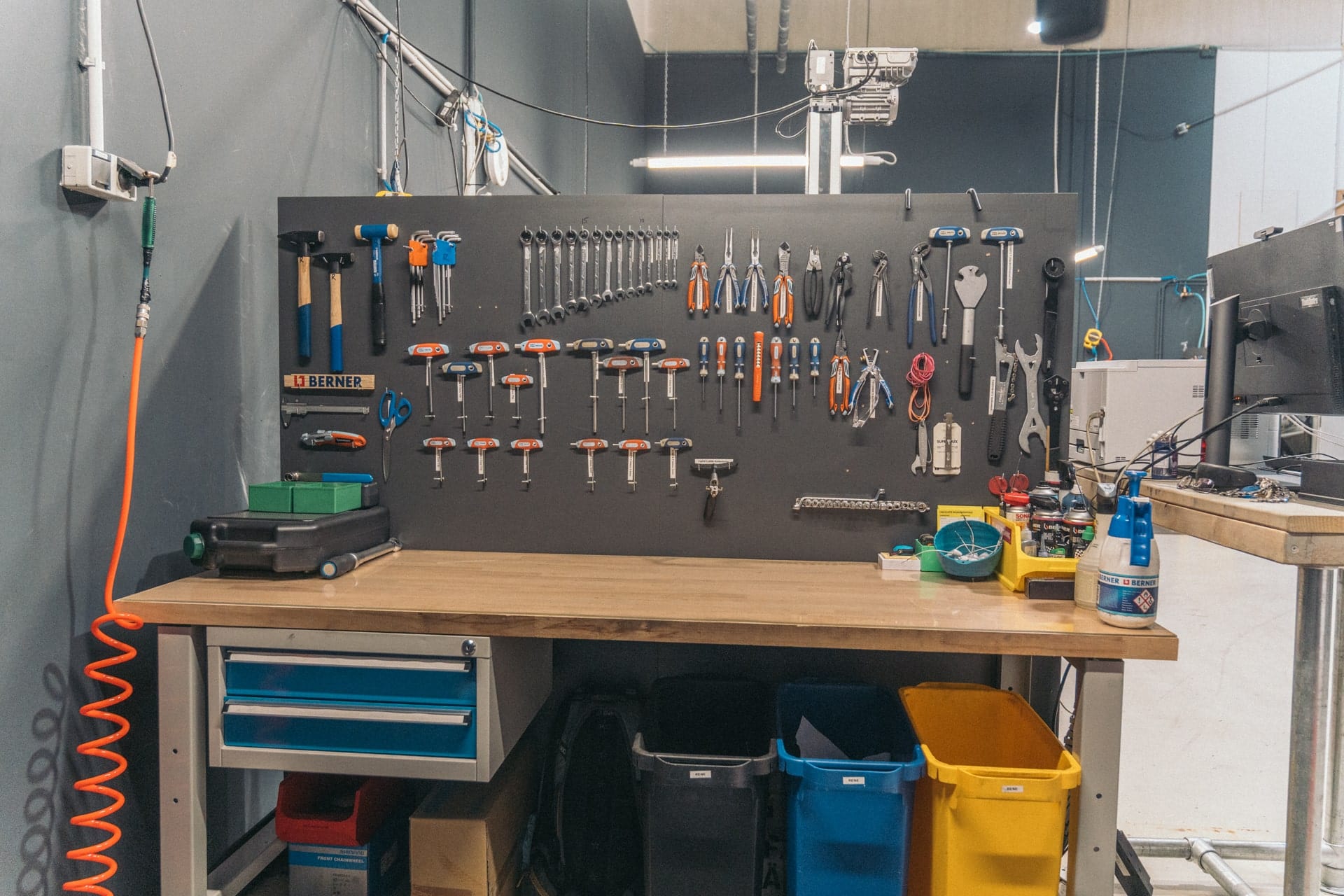 Werkbank in Fahrradwerkstatt mit Werkzeugwand, organisiert für Reparaturen und Wartung bei Lucky Bike.