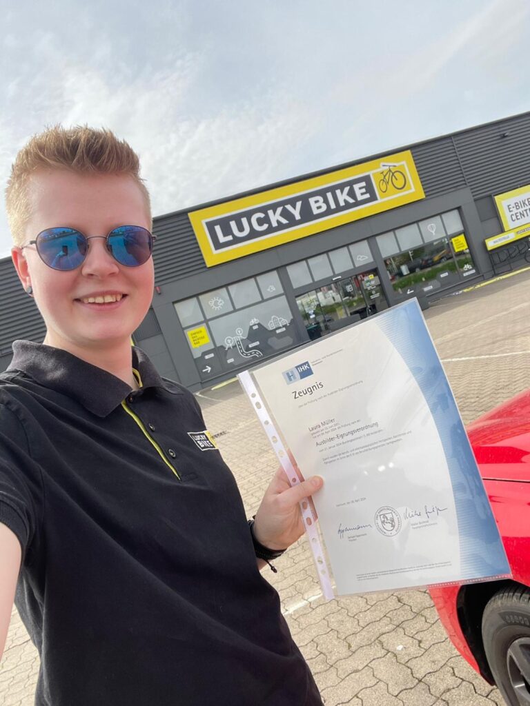 Laura Müller steht mit Zeugnis vor der Lucky Bike Filiale in Hildesheim