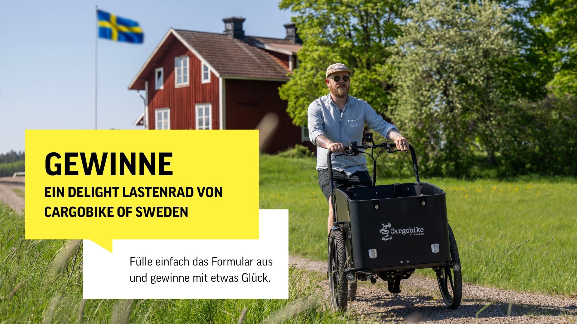 Gewinnspielbild mit Lastenrad-fahrenden Mann auf einem Schotterweg. Im Hintergrund ist ein rotes Haus und eine schwedische Flagge zu sehen.