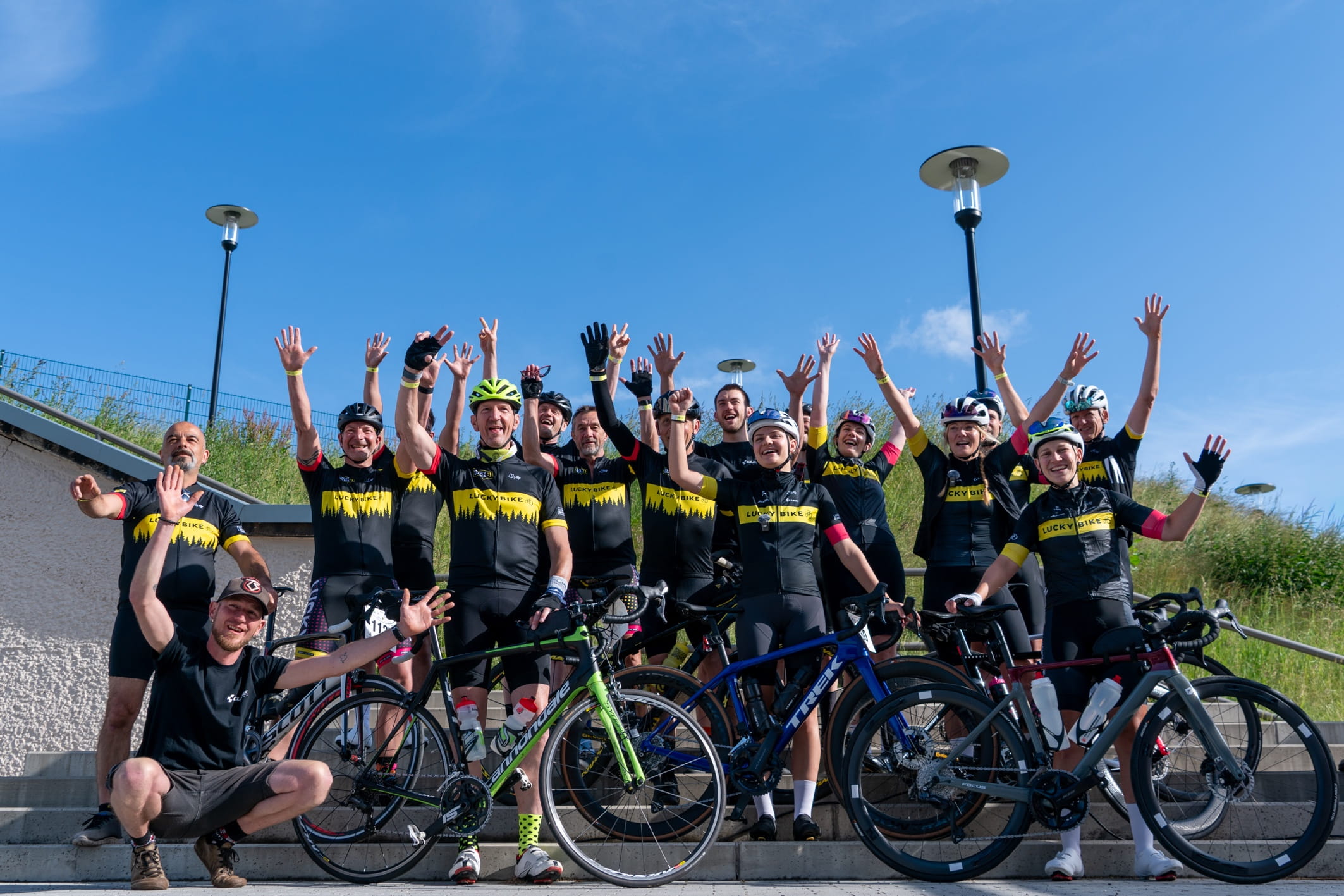Gruppenbild von jubelnden Menschen in FahrradTrikots von Lucky Bike gekleidet