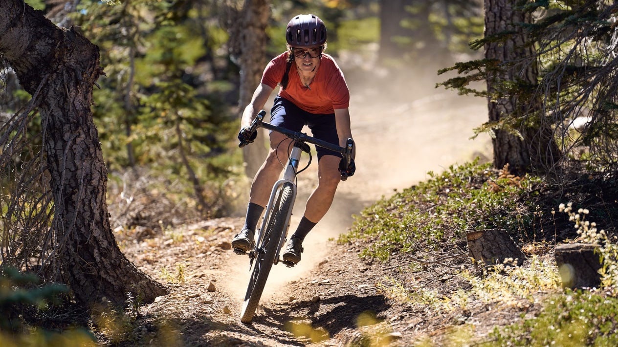 Gravelbike Fahrerin auf Wald-Trail mit Fahrradhelm und Fahrradbrille