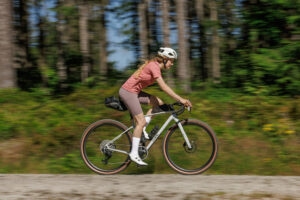 Seitenansicht einer Person, die auf einem Gravelbike in der Natur fährt