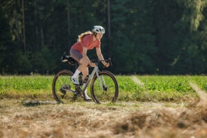 Seitenansicht einer Person, die auf einem Gravelbike in der Natur fährt