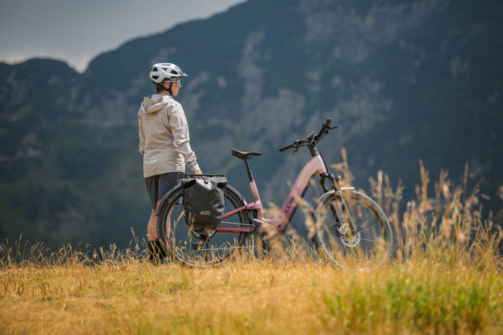 Perspektive von hitnen auf eine Person, die neben einem E-Bike von Cube steht in ländlicher Umgebung